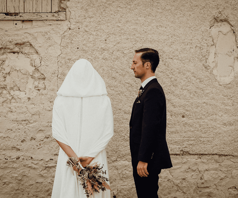 fotografia de una pareja el dia de su boda, ella está de espaldas mirando a la pared y el de perfil mirándole a ella