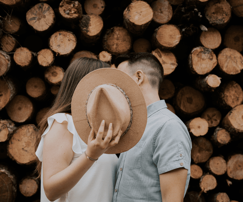 foto de una pareja dandose un beso tapandose tras un sombrero marron agarrado por ella