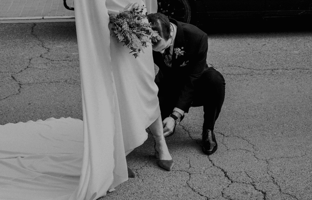 fotografia de un novio atando el zapato a su esposa el dia de su boda