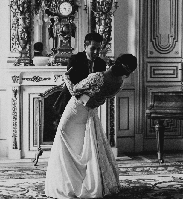 fotografia en blanco y negro de una pareja el dia de su boda bailando en el salon de un palacio