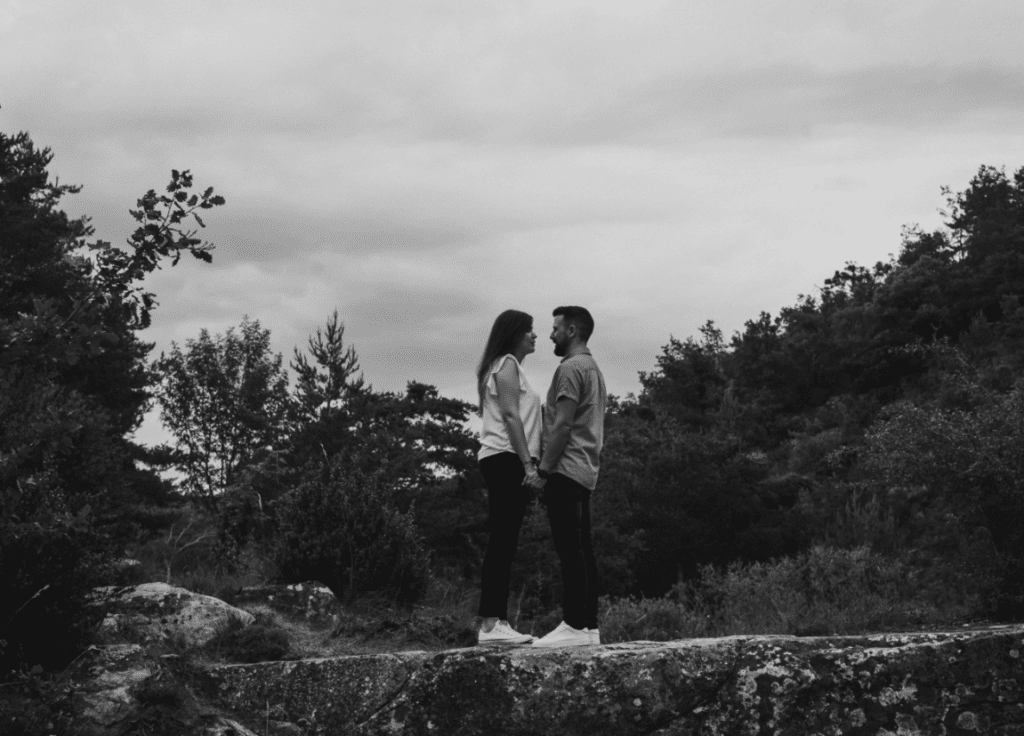 fotografia en blanco y negro de una pareja dandose la mano en un bosque
