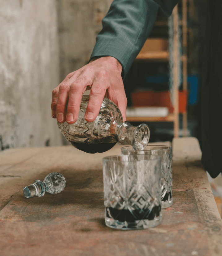 fotografia de la mano de un hombre sirviendose coñac en un baso